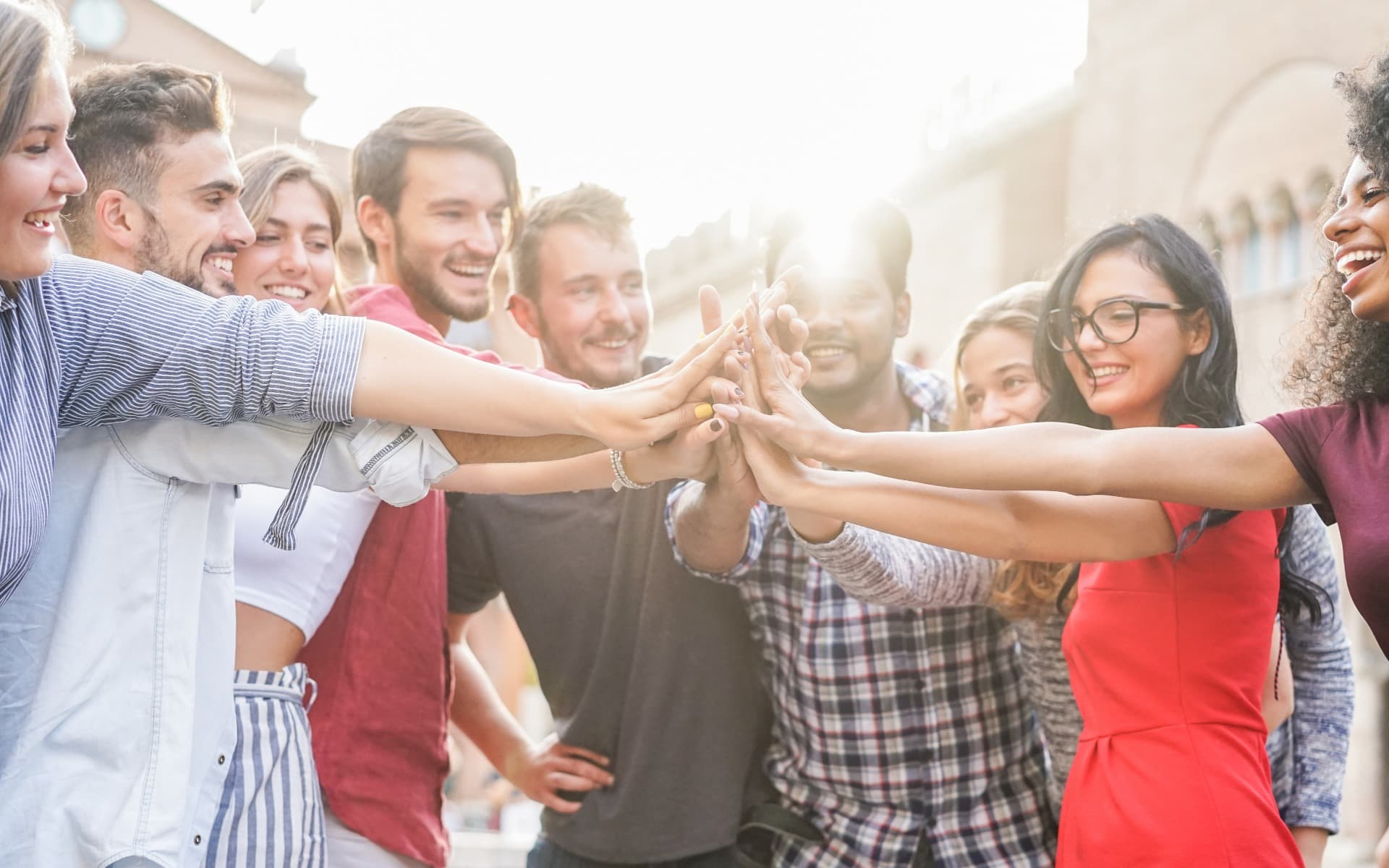 Young students stacking hands outdoor in college campus